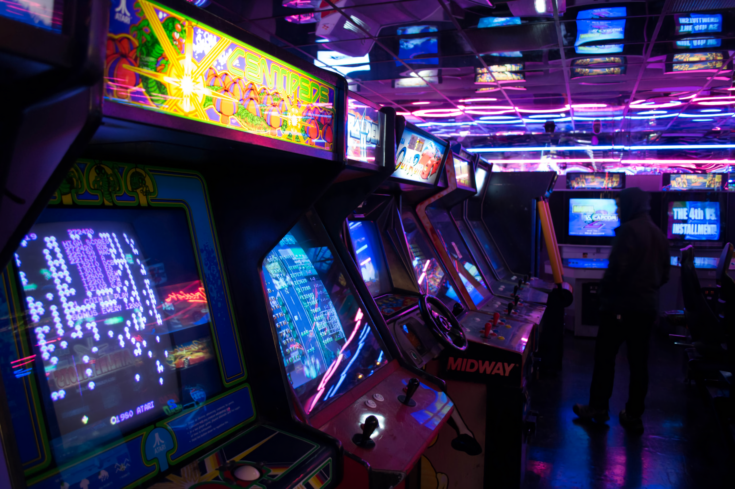 The meme is a photo of a dimly lit arcade, with rows of old video games and neon lights illuminating the space. The image is captioned "When you're trying to be a gamer but you're really just a grandma".